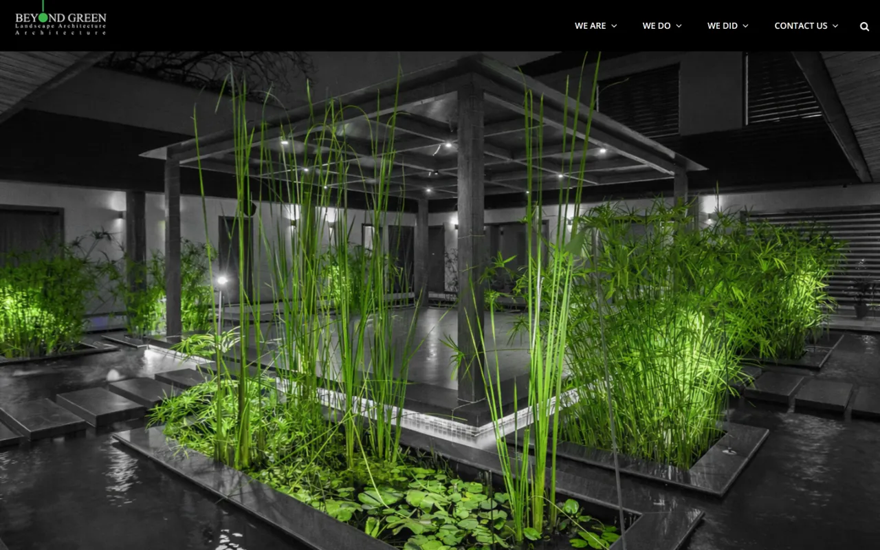 Beyond Green homepage on a desktop screen: a pergola at night above a water garden, its grasses lit bright green against a black-and-white courtyard.